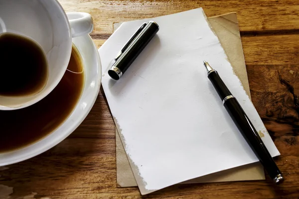 Taza de café con bloc de notas grunge y pluma sobre fondo de madera — Foto de Stock