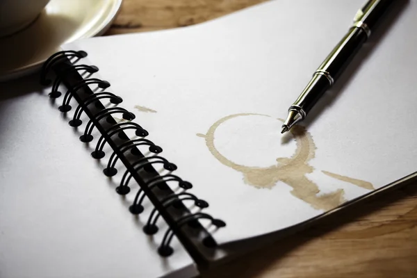Taza de café, cuaderno en espiral y pluma en el fondo de la mesa de madera — Foto de Stock
