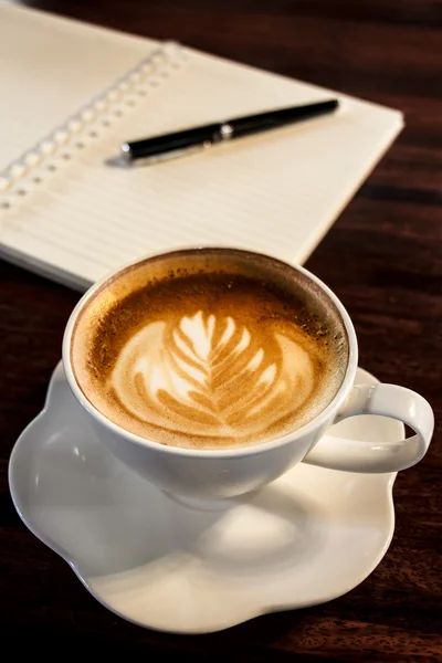 Taza de café, cuaderno en espiral y pluma en el fondo de la mesa de madera — Foto de Stock