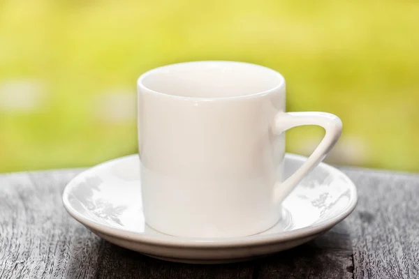Bílý šálek kávy na stole s pozadím krajina — Stock fotografie