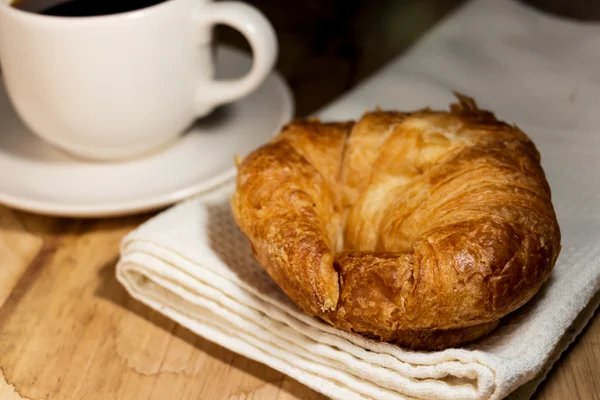 Café y croissant sobre mesa de madera — Foto de Stock