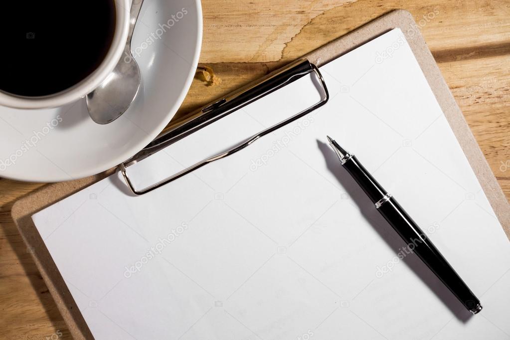 blank white notebook, pen and cup of coffee on the desk