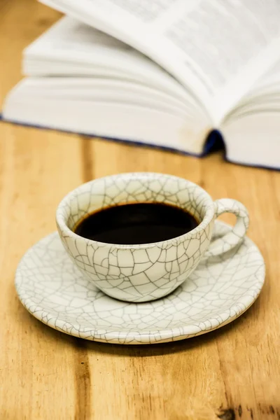 Xícara de café e livro aberto sobre mesa de madeira — Fotografia de Stock