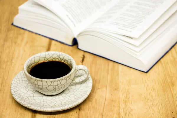 Cup of coffee and opened book on wood table — Stock Photo, Image