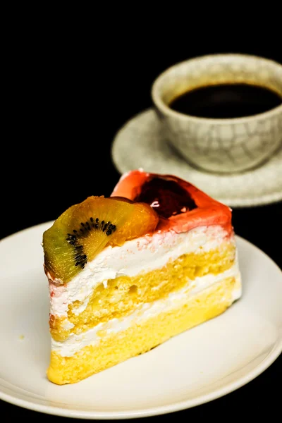 Чашка кави та фруктовий торт на чорному фоні — стокове фото