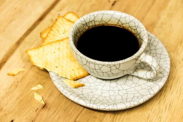 Tasse Kaffee mit Crackern auf Holztisch. — Stockfoto