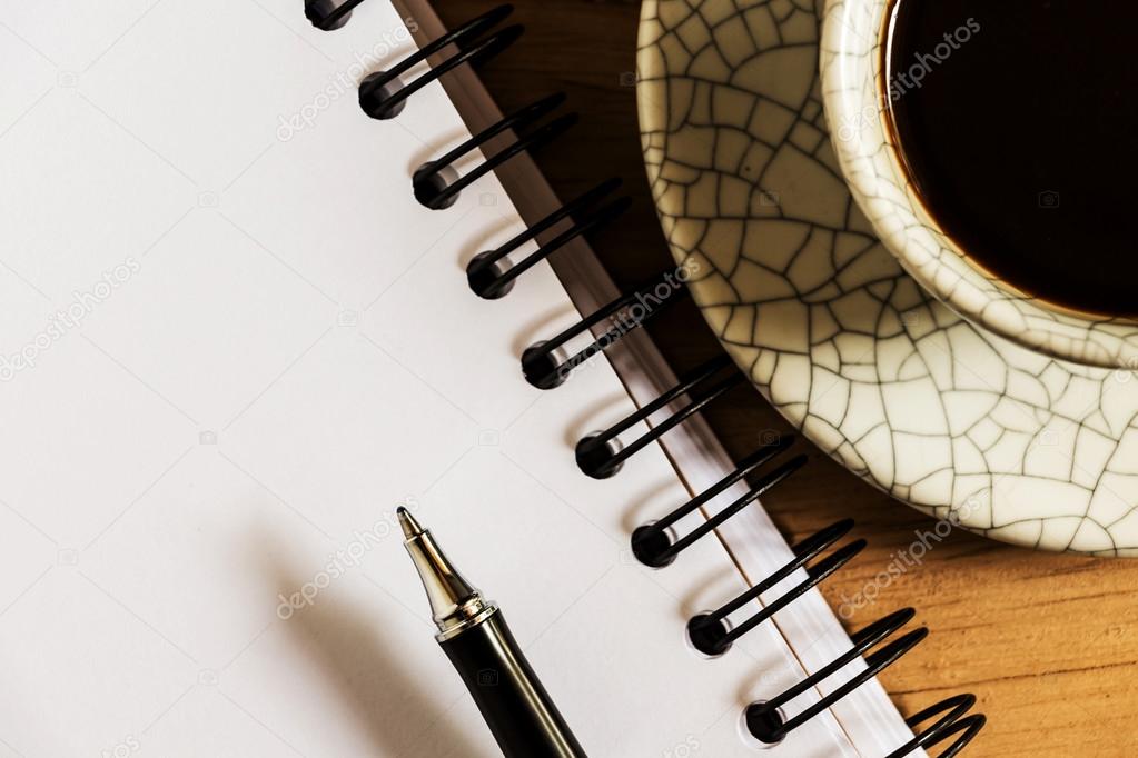 work desk with paper, pen and cup of instant coffee