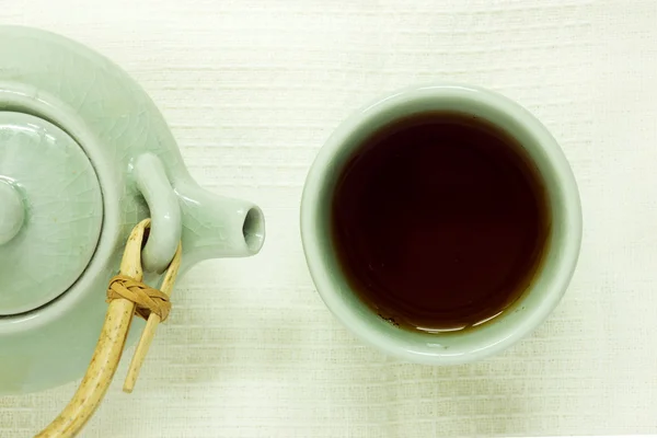Xícara de chá com um bule na toalha de mesa branca . — Fotografia de Stock