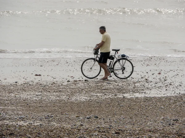 Mann schiebt Fahrrad am Strand entlang — Stockfoto