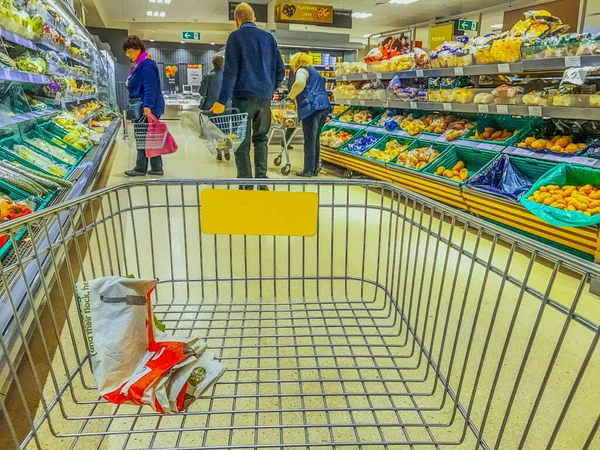 イギリスのスーパーマーケットの内部前景にあるイギリスのショッピングトロリー — ストック写真