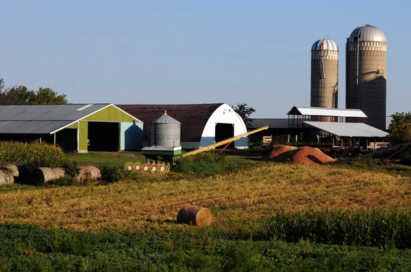 Fazenda no campo com equipamentos agrícolas, máquinas e celeiro — Fotografia de Stock