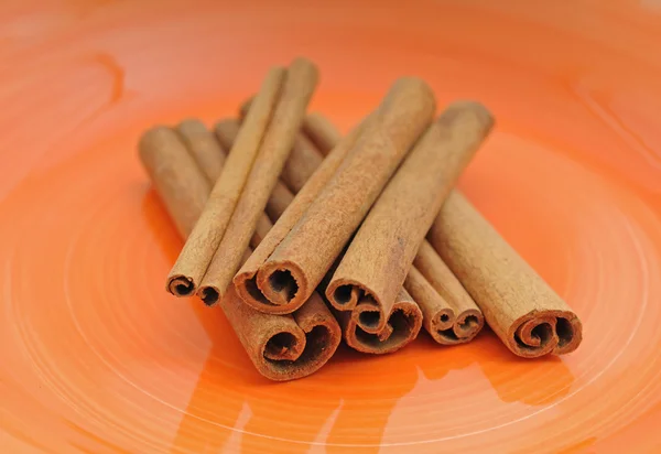 Коричные палочки на оранжевой тарелке — стоковое фото