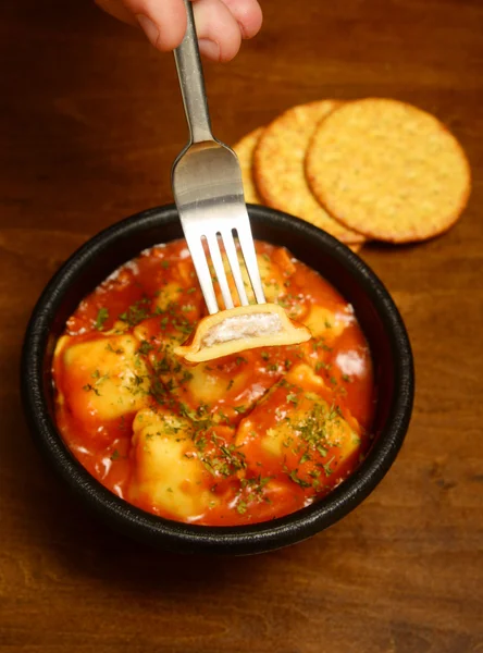 Hand holding ravioli on fork and wood background — Stock Photo, Image