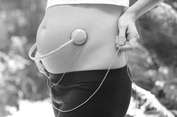 Mulher grávida tocando música para o bebê por nascer — Fotografia de Stock