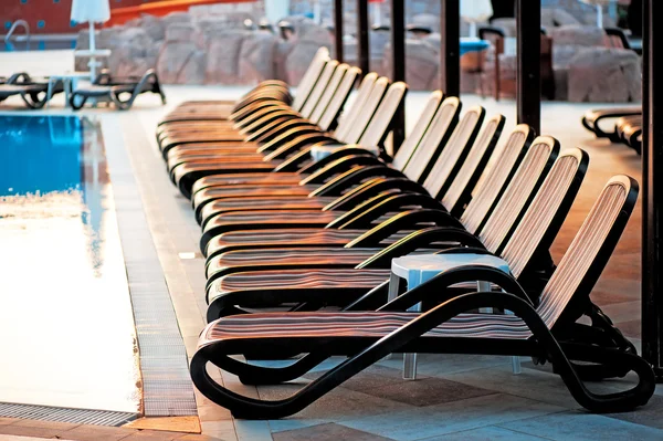 Mehrere Liegestühle am Pool bei Sonnenaufgang. — Stockfoto