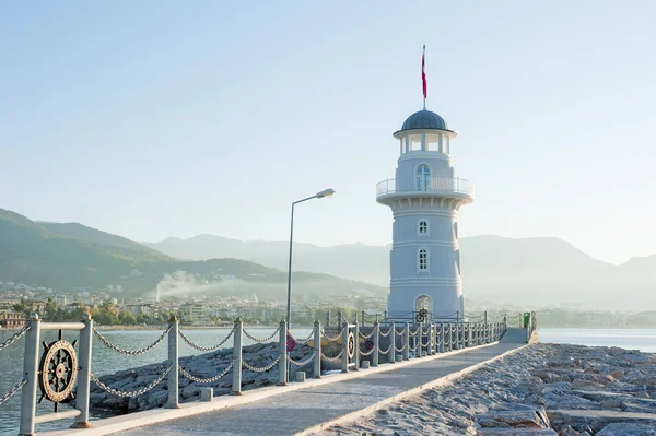 Paisaje con un faro en la ciudad portuaria de Alanya al amanecer . — Foto de Stock