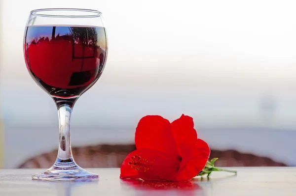 Glas rode wijn met een bloem bij zonsondergang. — Stockfoto