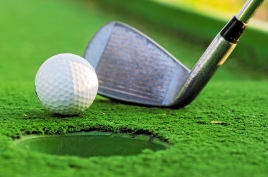 Golf topu deliğe yeşil sahada yakınındaki.