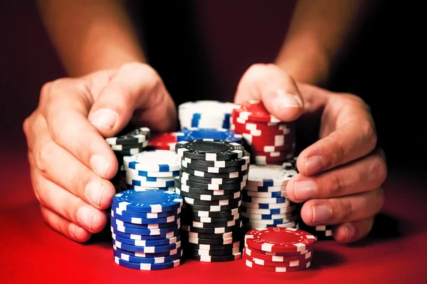 Man's hands move the winnings casino chips on red table — Stock Photo, Image