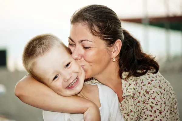 Mère embrassant la joue de son enfant — Photo