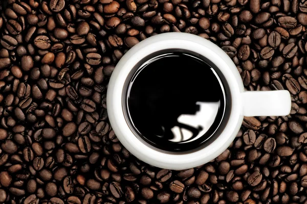 Une tasse de café sur un fond grains de café — Photo