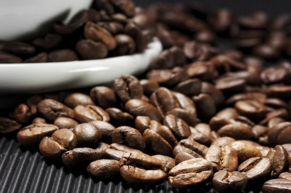 Des grains de café éparpillés sur une rainure noire — Photo
