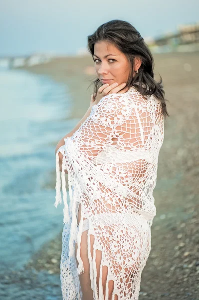Retrato de una hermosa chica en un chal blanco en la playa . — Foto de Stock