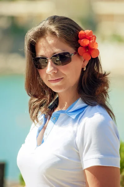 Retrato de una hermosa chica con una flor roja en el pelo —  Fotos de Stock