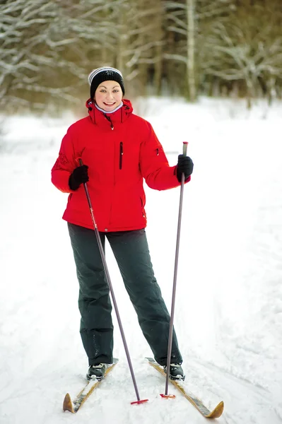 Szczęśliwa dziewczyna pozuje na narty w lesie zimą. — Zdjęcie stockowe