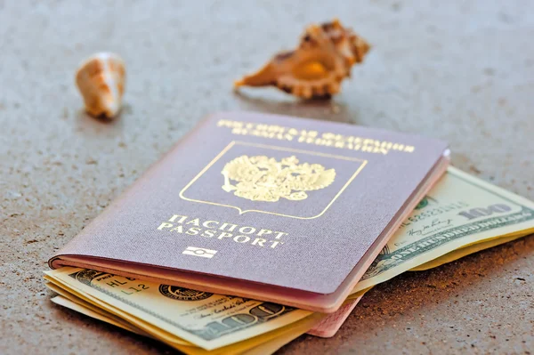 Russian passport with a dollar invested and seashells on a granite table top — Stock Photo, Image