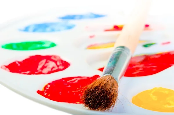 Pincel de artista sobre una paleta blanca con pinturas — Foto de Stock