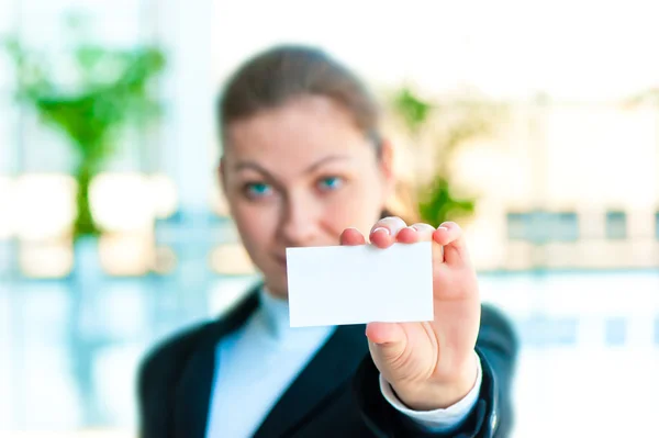 A smiling girl in costume shows a blank business card — Stock Photo, Image