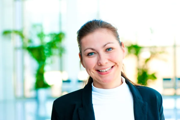 Портрет улыбающейся девушки на фоне расфокусированного офисного интерьера менеджера — стоковое фото
