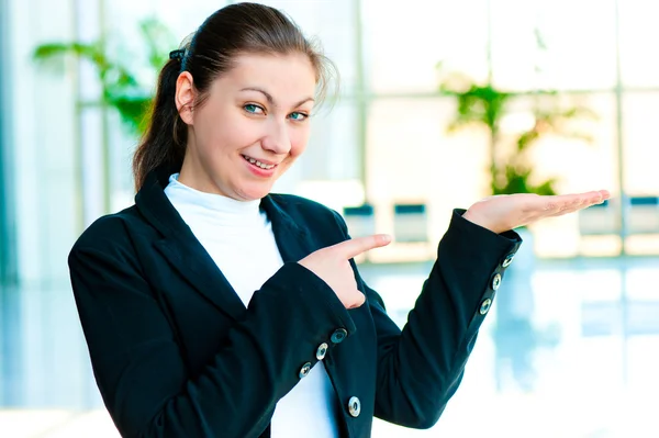 Happy young woman holding something on the palm of your hand and points a finger at her — Stock Photo, Image