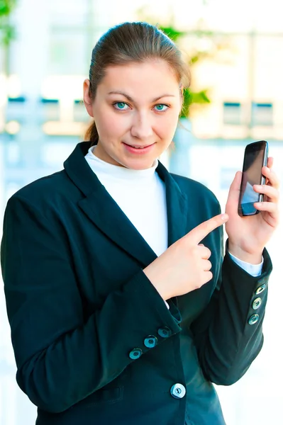 Atractivo joven morena muestra en su teléfono inteligente — Foto de Stock