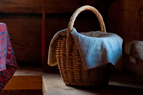 Rieten mand met een handdoek op een houten bank in een dorpshuis — Stockfoto