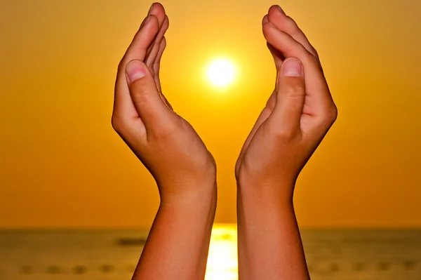 Sol sobre el mar en manos femeninas — Foto de Stock