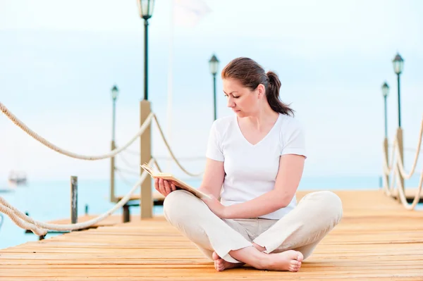 Junges Mädchen liest im Sitzen ein Buch — Stockfoto