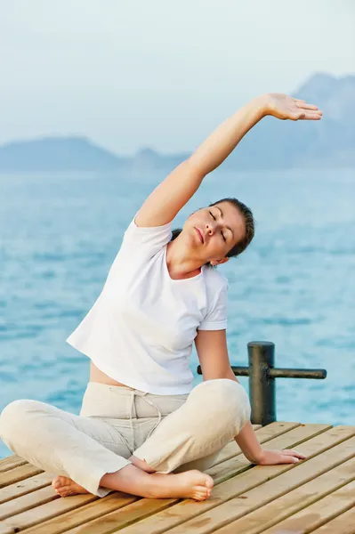 Mladá žena v pilates u moře — Stock fotografie