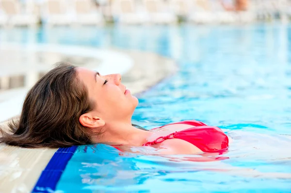 Beautiful girl relaxes in the pool with your eyes closed — Stock Photo, Image