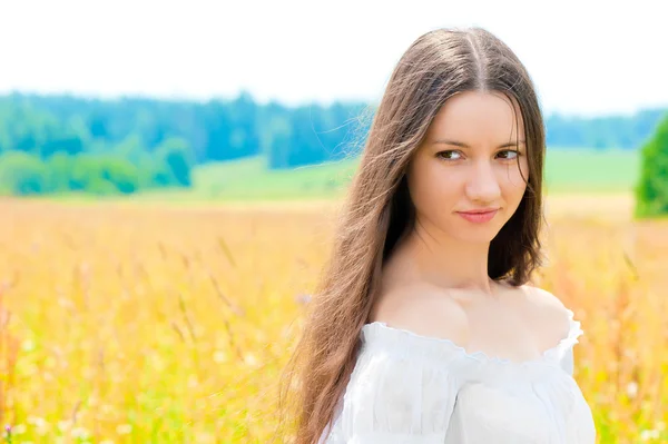 Hermosa joven rusa en un campo con espigas de oro de trigo —  Fotos de Stock