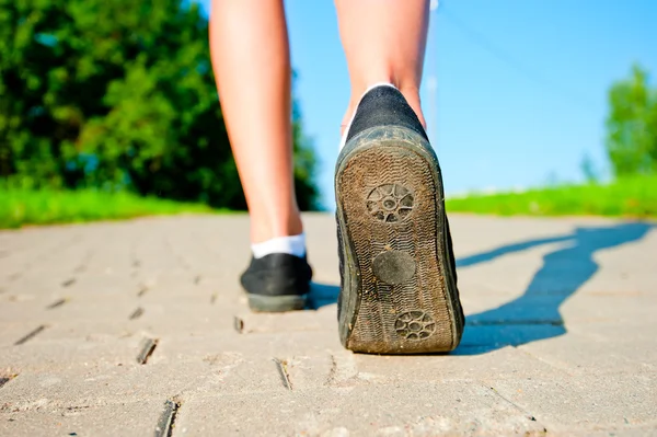 Kvinnliga ben i sneakers närbild kör på vägen på morgonen — Stockfoto