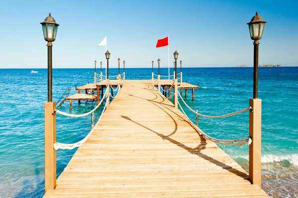 Lichtmasten en touw hek op houten pier — Stockfoto