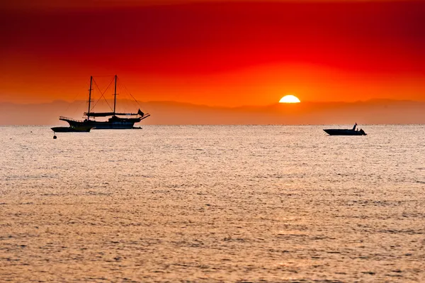 Red sunset behind the mountains over the sea and ships — Stock Photo, Image