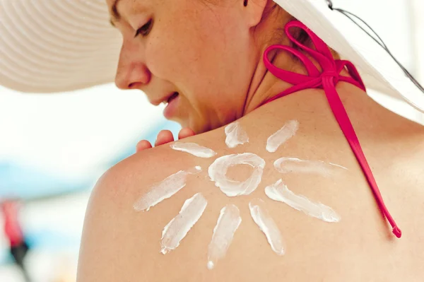 Crema solar dibujada en su hombro una hermosa mujer joven —  Fotos de Stock