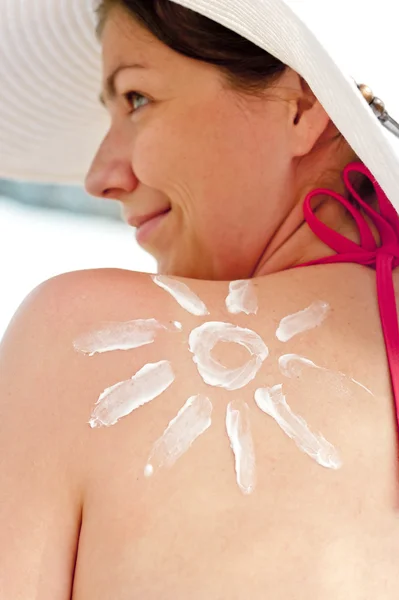 Ragazza sulla spiaggia con narisovanna crema solare spalla — Foto Stock