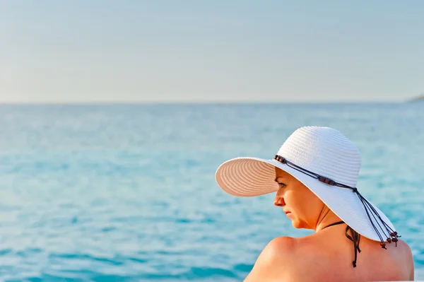 Ritratto di una giovane donna con un cappello bianco sullo sfondo del mare — Foto Stock