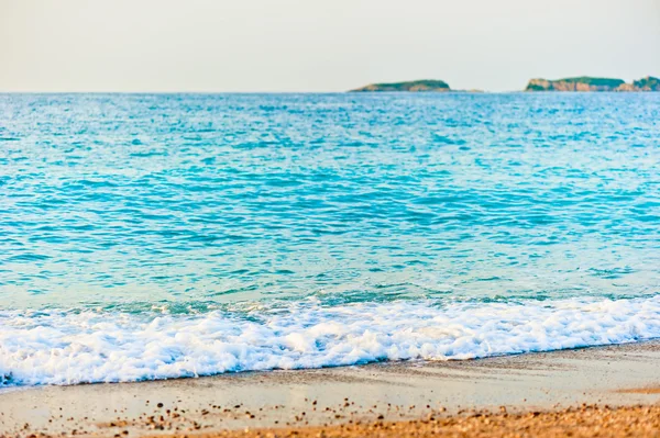 Aqua turquoise sea rolls on the beach at dawn — Stock Photo, Image