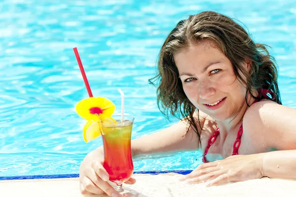 Morena encantadora na piscina segurando um copo de coquetel alcoólico — Fotografia de Stock