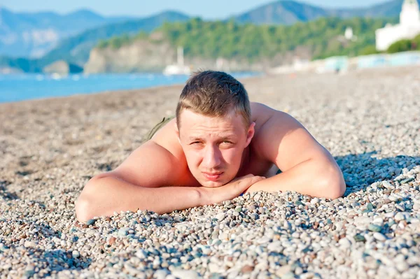 Kayalık bir sahilde yatan adam sunbathes — Stok fotoğraf